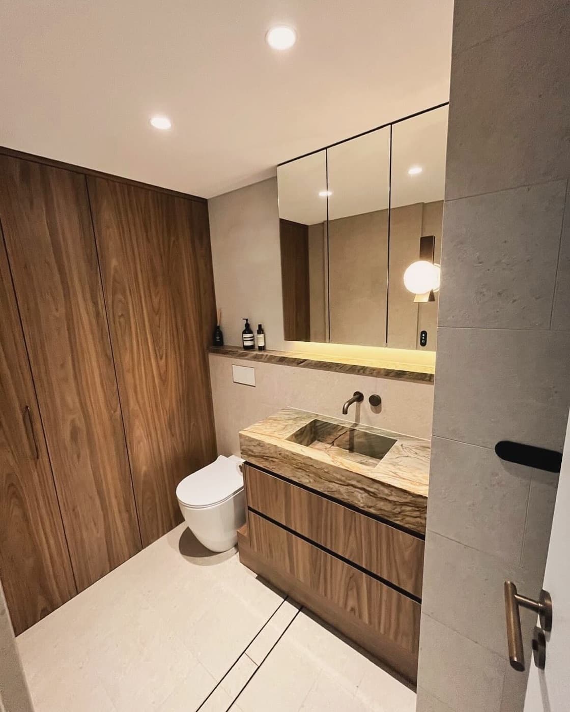 A bathroom lit by LED downlights and a backlit mirror