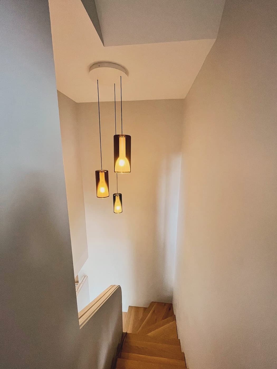 Amber glass pendants hanging down a white stairwell